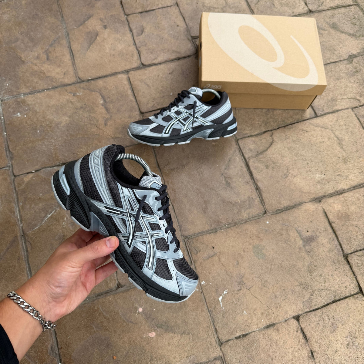ASICS Gel-1130 Graphite Grey Gravel trainers held in hand