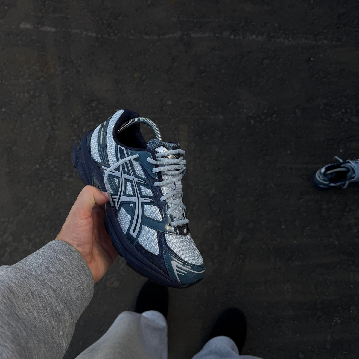 ASICS Gel-1130 Piedmont Blue trainer held at an angle showing the mesh and synthetic panel construction