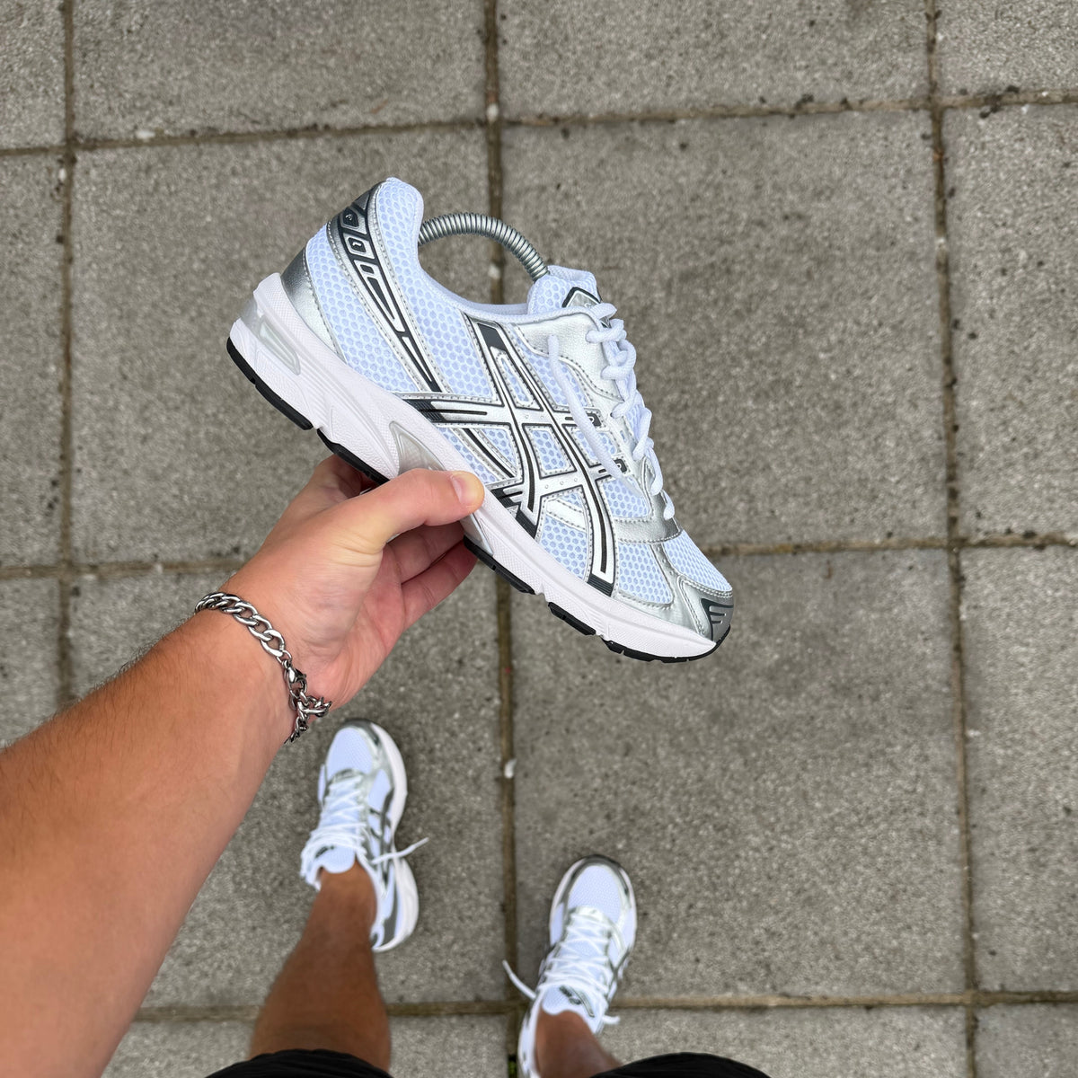 Side profile of ASICS Gel-1130 White Pure Silver held by hand highlighting the layered technical upper