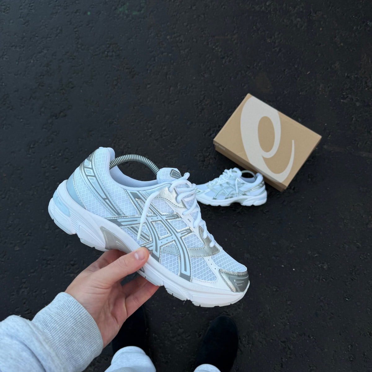 ASICS GEL-1130 White Storm Cloud trainer photographed at an angle beside original ASICS shoebox
