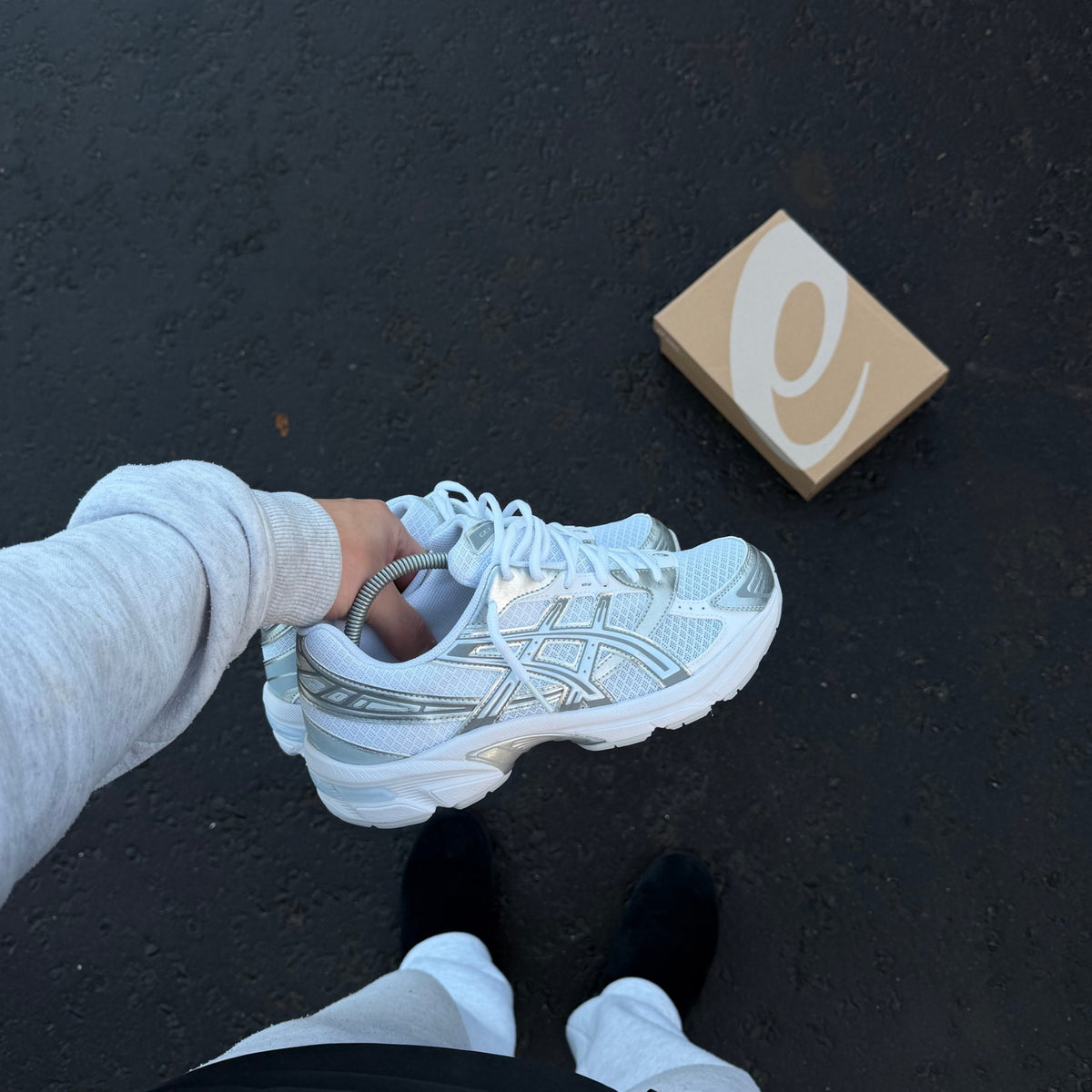 ASICS GEL-1130 White Storm Cloud trainer held in hand showing white mesh upper, grey ASICS stripes and silver detailing