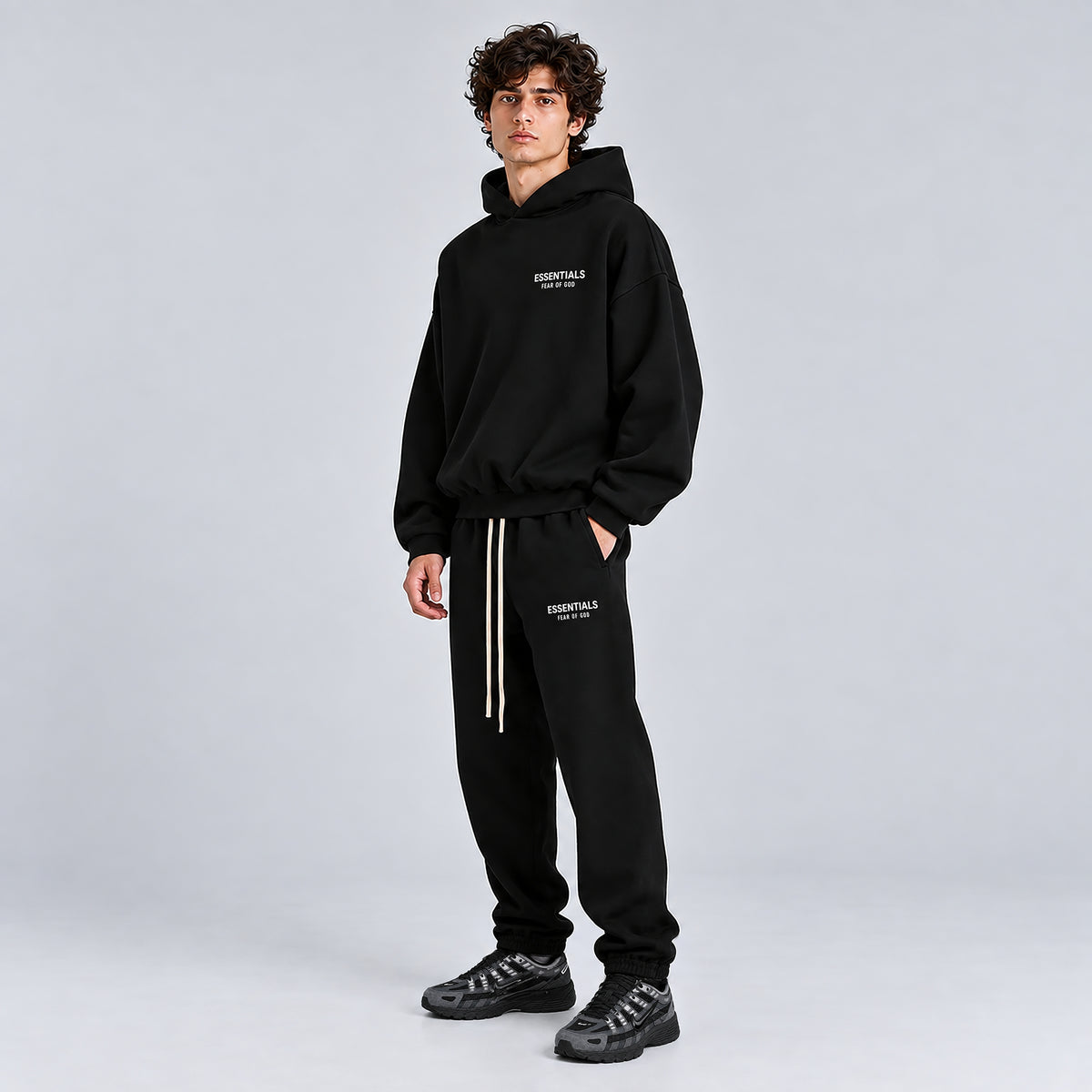 Side model view of Fear of God Essentials Hoodie Black FW24 showing the relaxed fit and silhouette