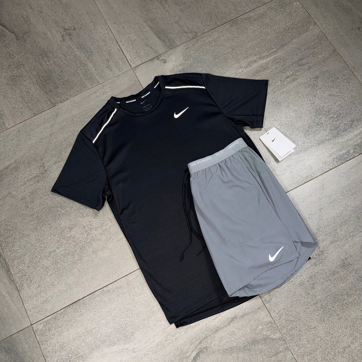 Angled flat lay of black Nike Miler running top paired with grey Nike Flex Stride shorts