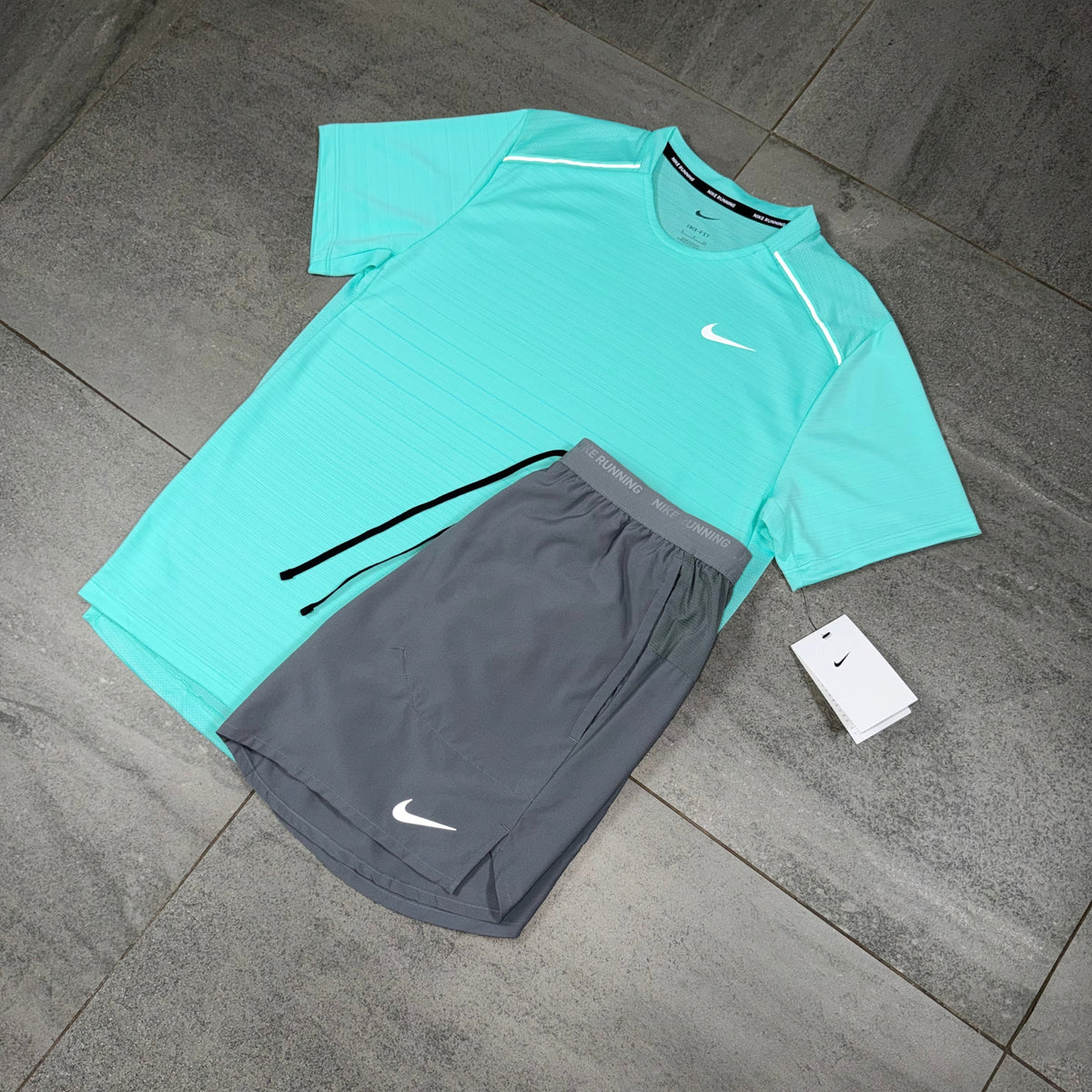 Hyper Turquoise Nike Miler shirt and grey running shorts arranged as a lightweight activewear set