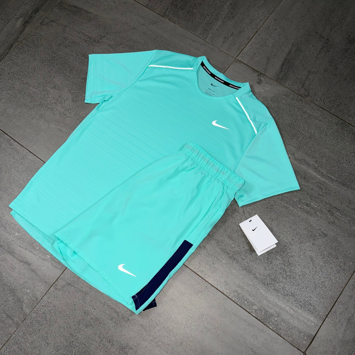 Hyper Turquoise Nike running set laid flat showing the Miler shirt and contrasting Challenger shorts