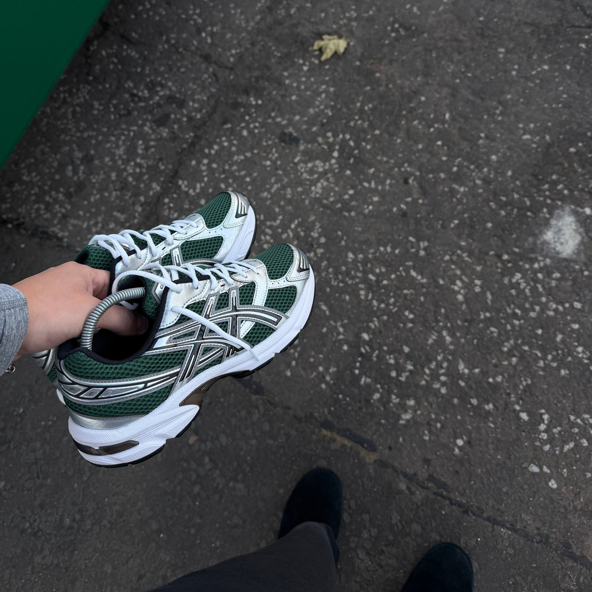 Close-up of ASICS GEL-1130 Evergreen Black trainers highlighting dark green mesh, silver detailing and retro running design