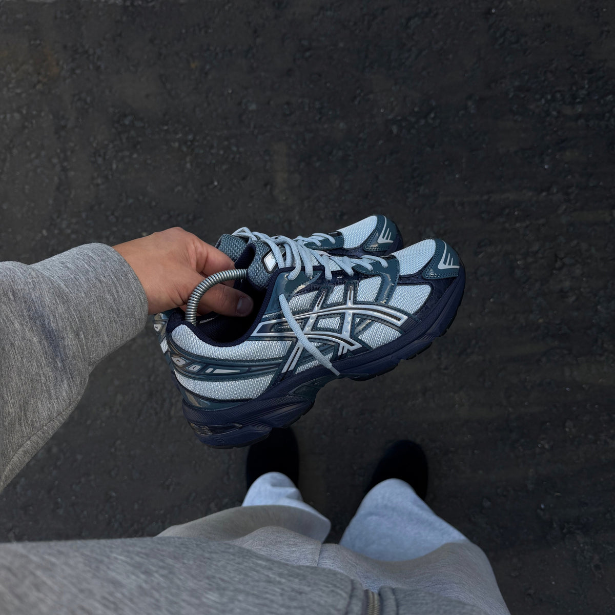 ASICS Gel-1130 Piedmont Blue trainers held in hand showing the blue mesh upper and layered ASICS detailing