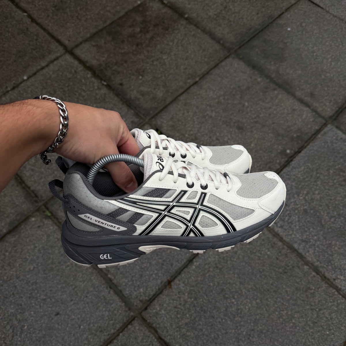ASICS Gel-Venture 6 Olive Grey Cream trainer held in hand showing cream mesh upper, grey overlays and ASICS side stripes