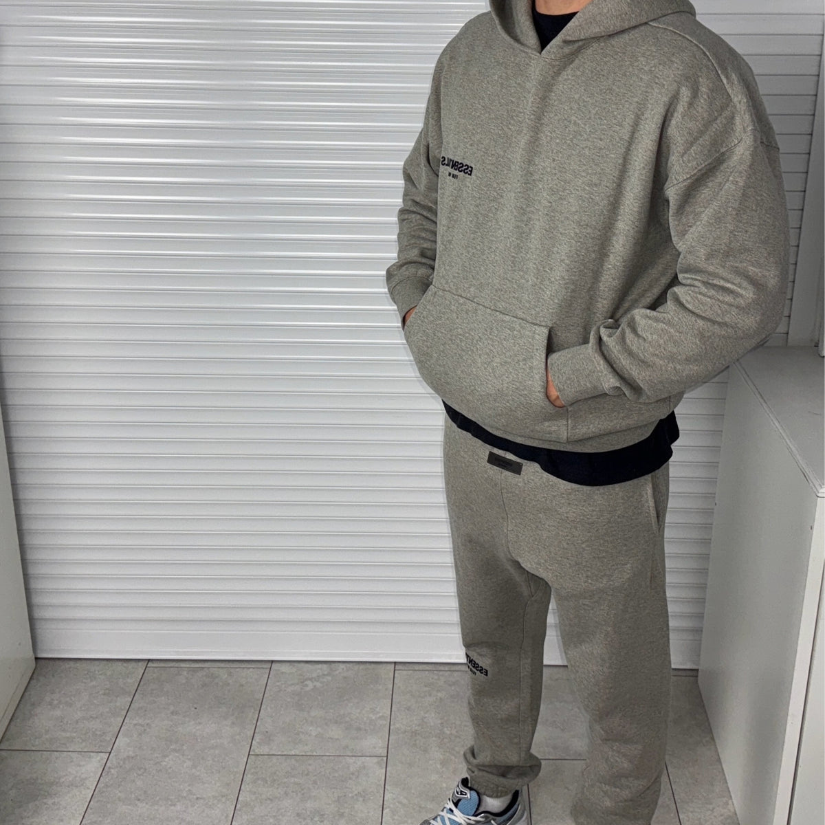 Fear of God Essentials Dark Heather Oatmeal Hoodie worn on body showing the kangaroo pocket and front fit