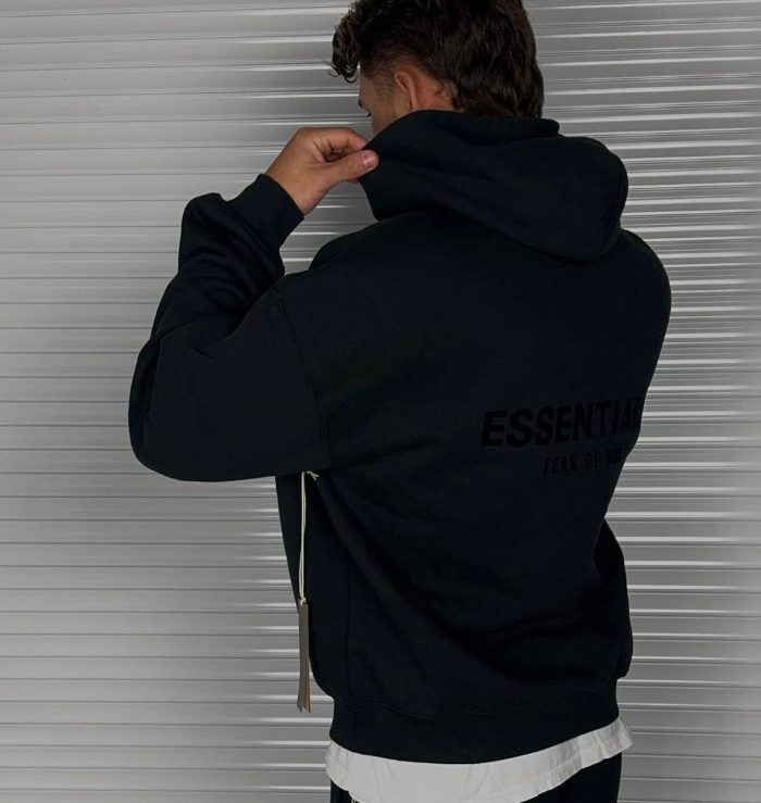 Close-up rear view of the Fear of God Essentials Black Hoodie showing the ESSENTIALS back branding