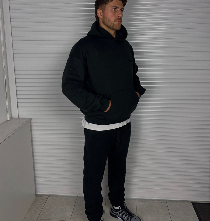 Side view of Fear of God Essentials Black Hoodie SS22 showing the oversized fit and kangaroo pocket