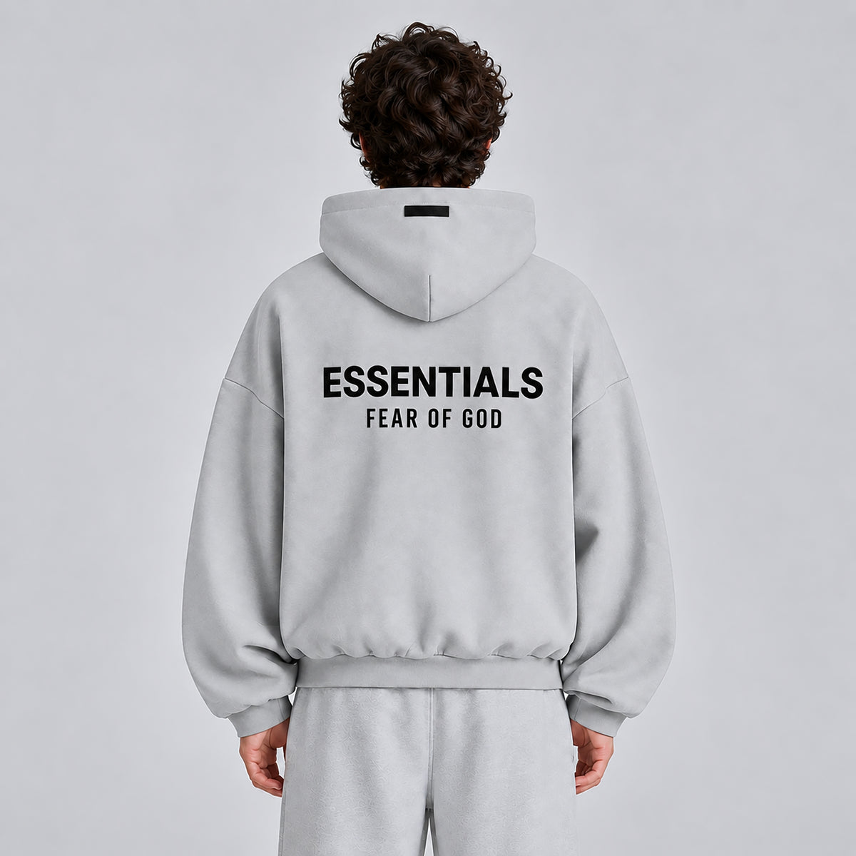 Back view of Fear of God Essentials Light Heather Grey FW24 hoodie showing ESSENTIALS branding