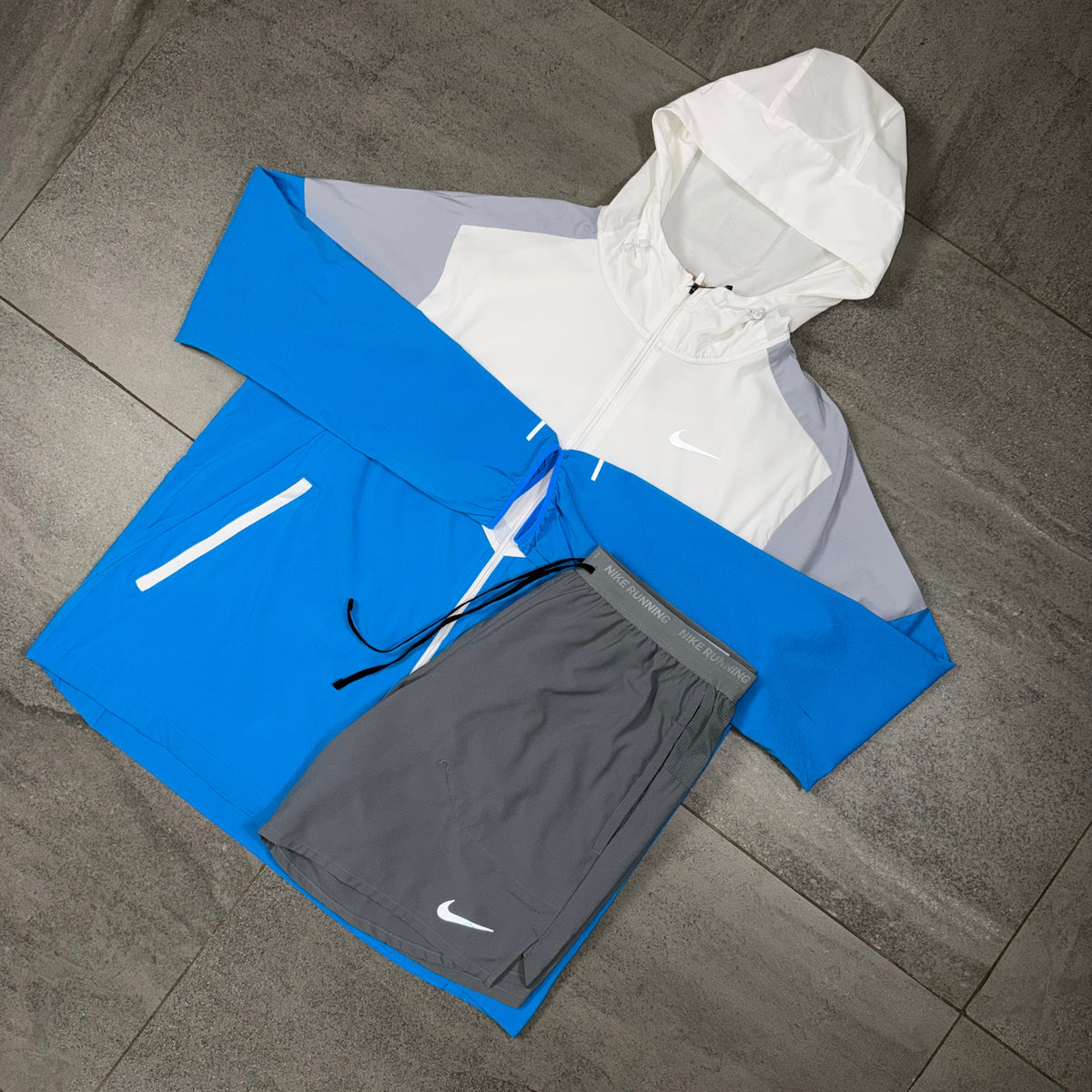 Blue and white Nike Windrunner alongside grey Flex Stride training shorts