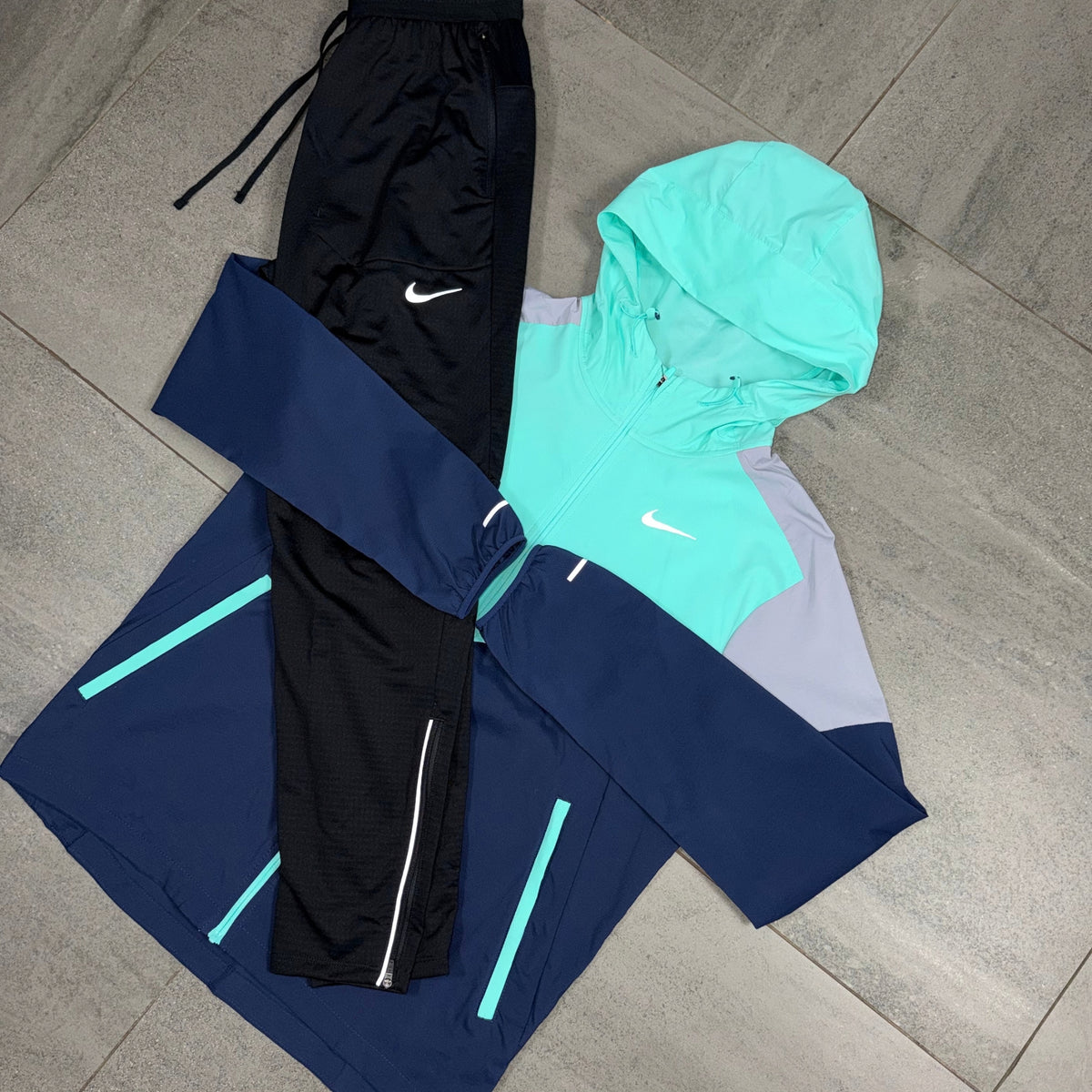 Nike Hyper Turquoise Windrunner jacket with Black Phenom pants flat lay