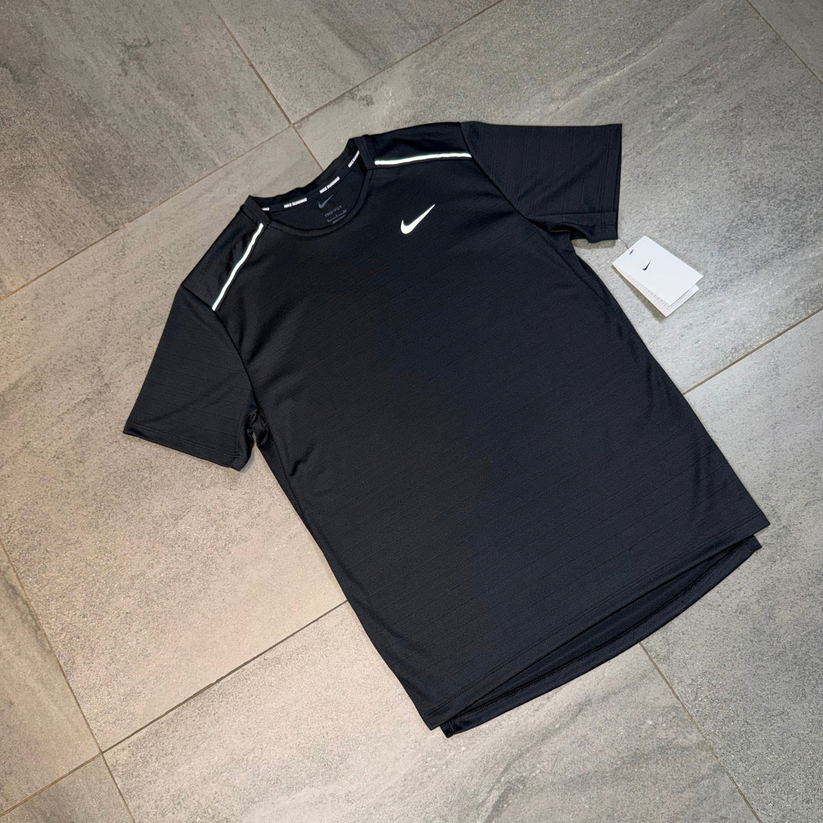 Black Nike Miler 1.0 activewear top displayed with the Nike Swoosh and streamlined running design