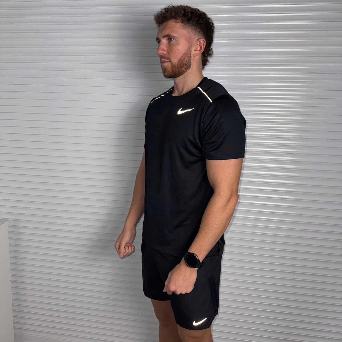 Full-length view of a model wearing the black Nike Miler 1.0 running T-shirt with black shorts
