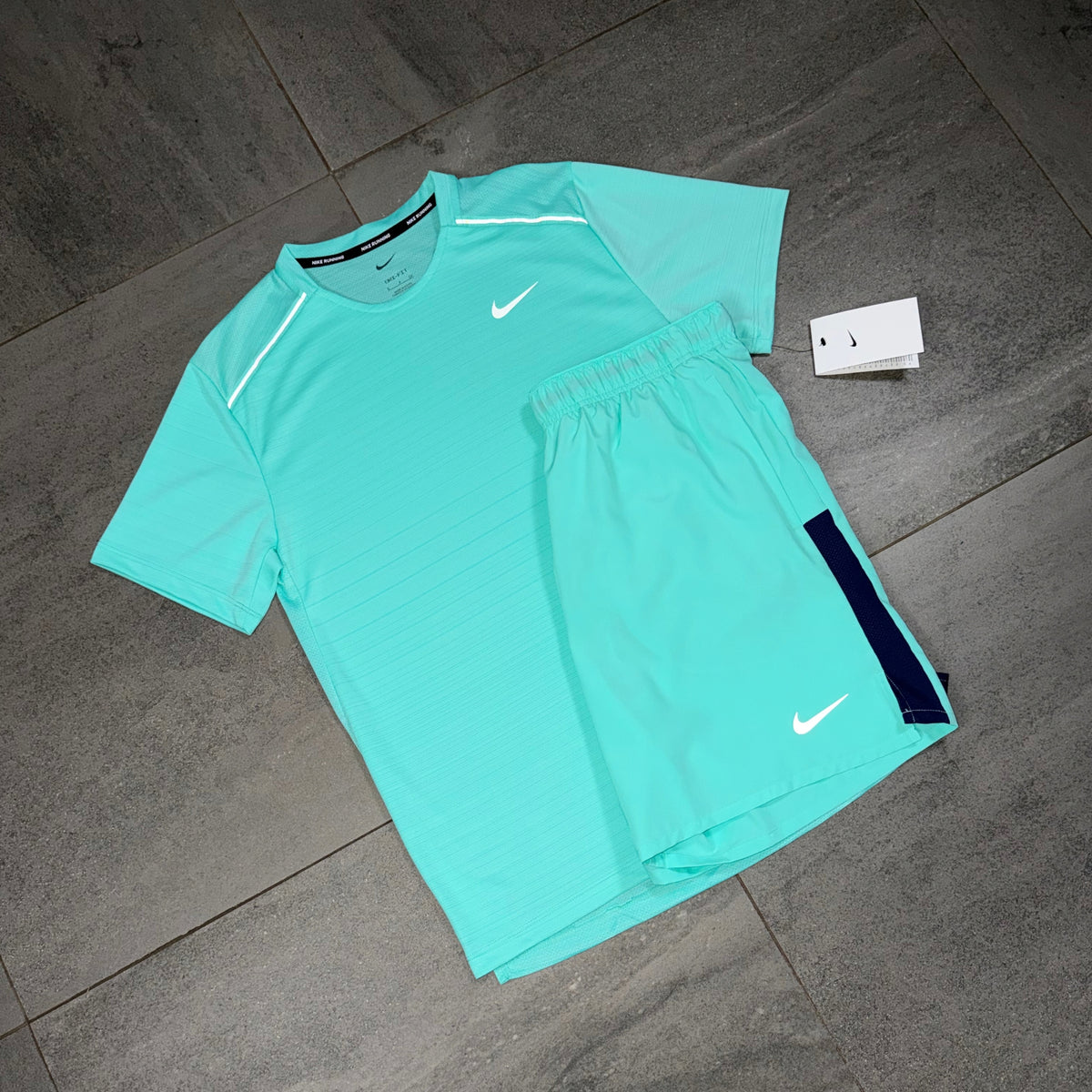 Angled flat lay of the turquoise Nike Miler top paired with Challenger performance shorts