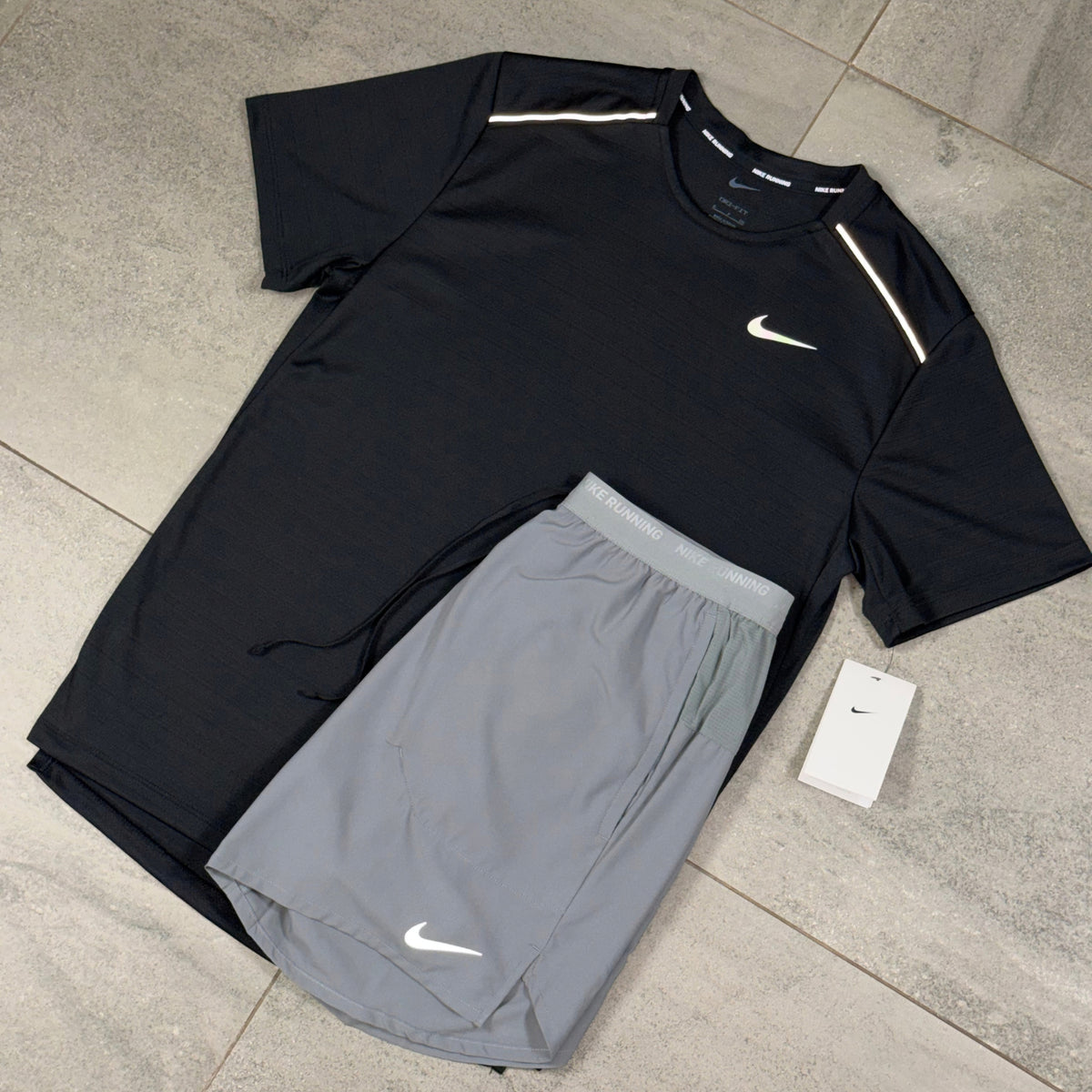 Close angled view of the black Nike Miler top and grey Flex Stride shorts arranged as a gym outfit