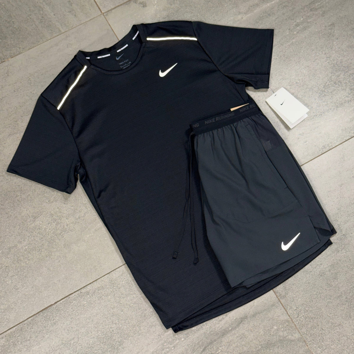 Black Nike Miler and Flex Stride training kit laid flat with product tags visible