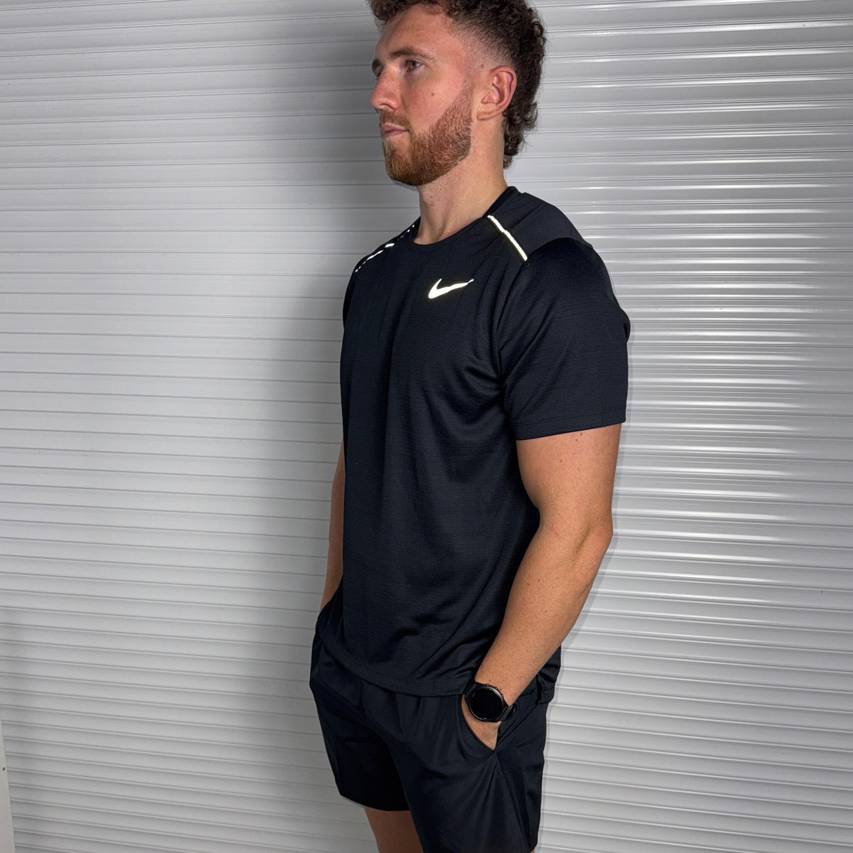 Model wearing the Nike Miler black performance T-shirt as part of the black and grey activewear set