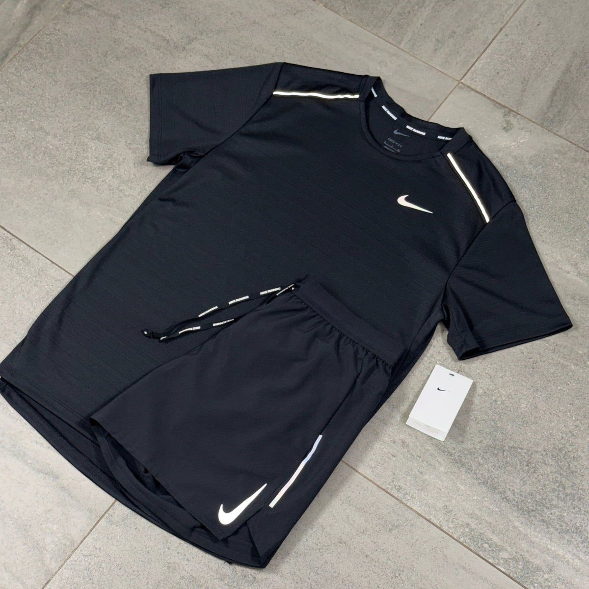 Angled flat lay of the all-black Nike Miler top with Nike OG Flex running shorts