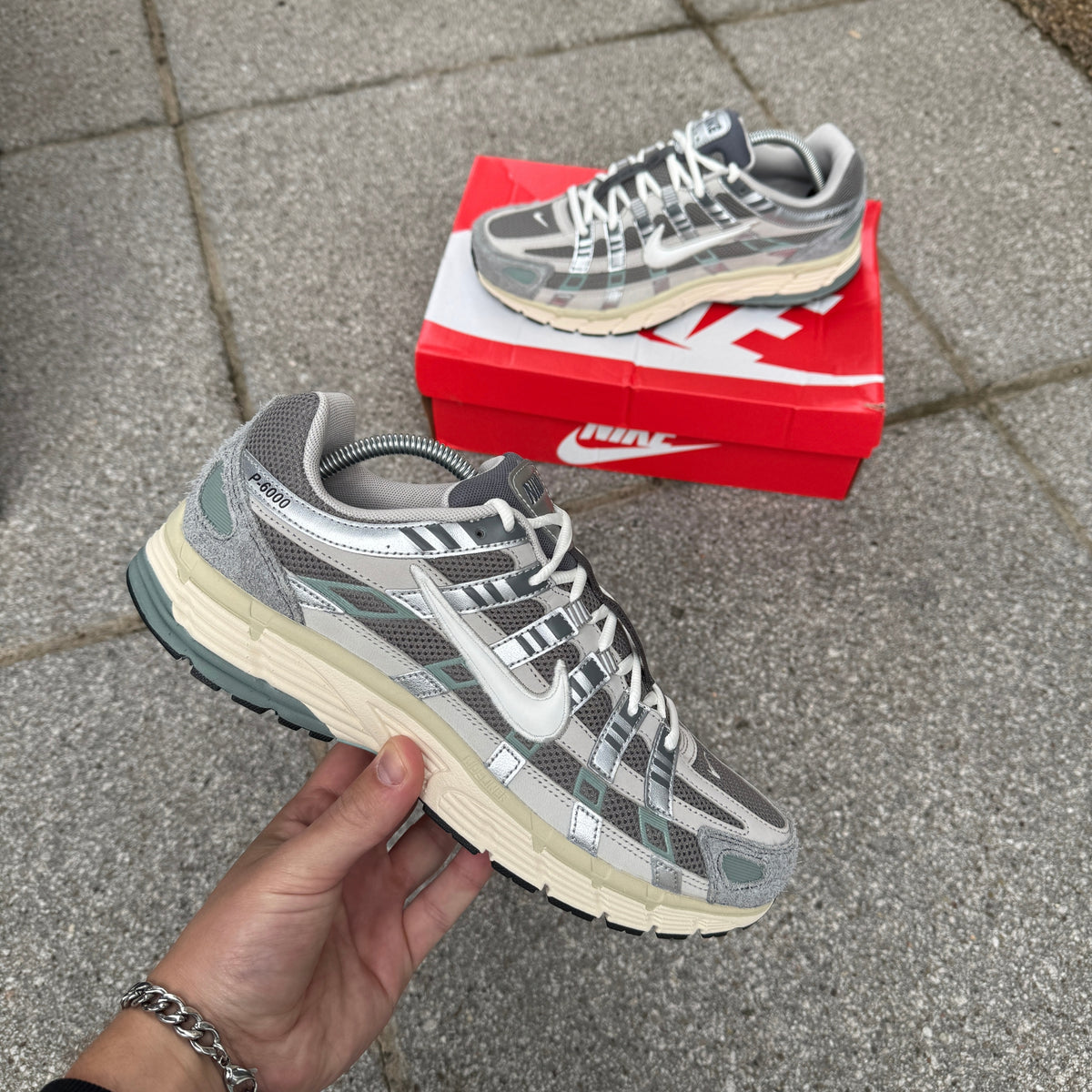 Nike P-6000 Flat Pewter grey trainers held in hand