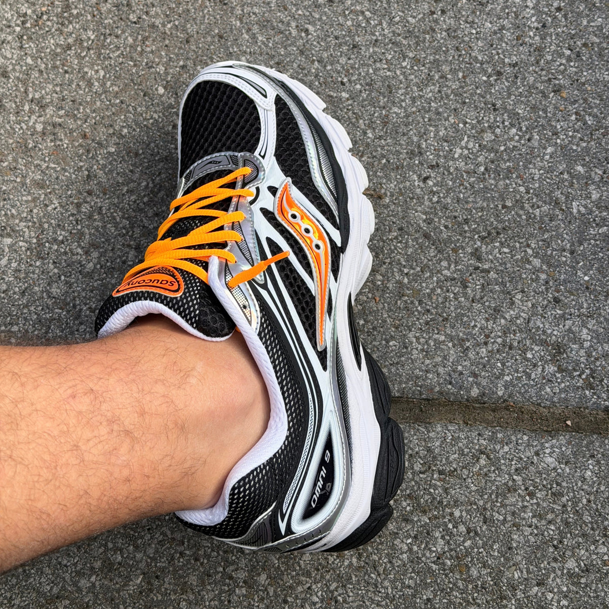 Saucony ProGrid Omni 9 White Orange trainers worn on feet showing the contrasting orange laces