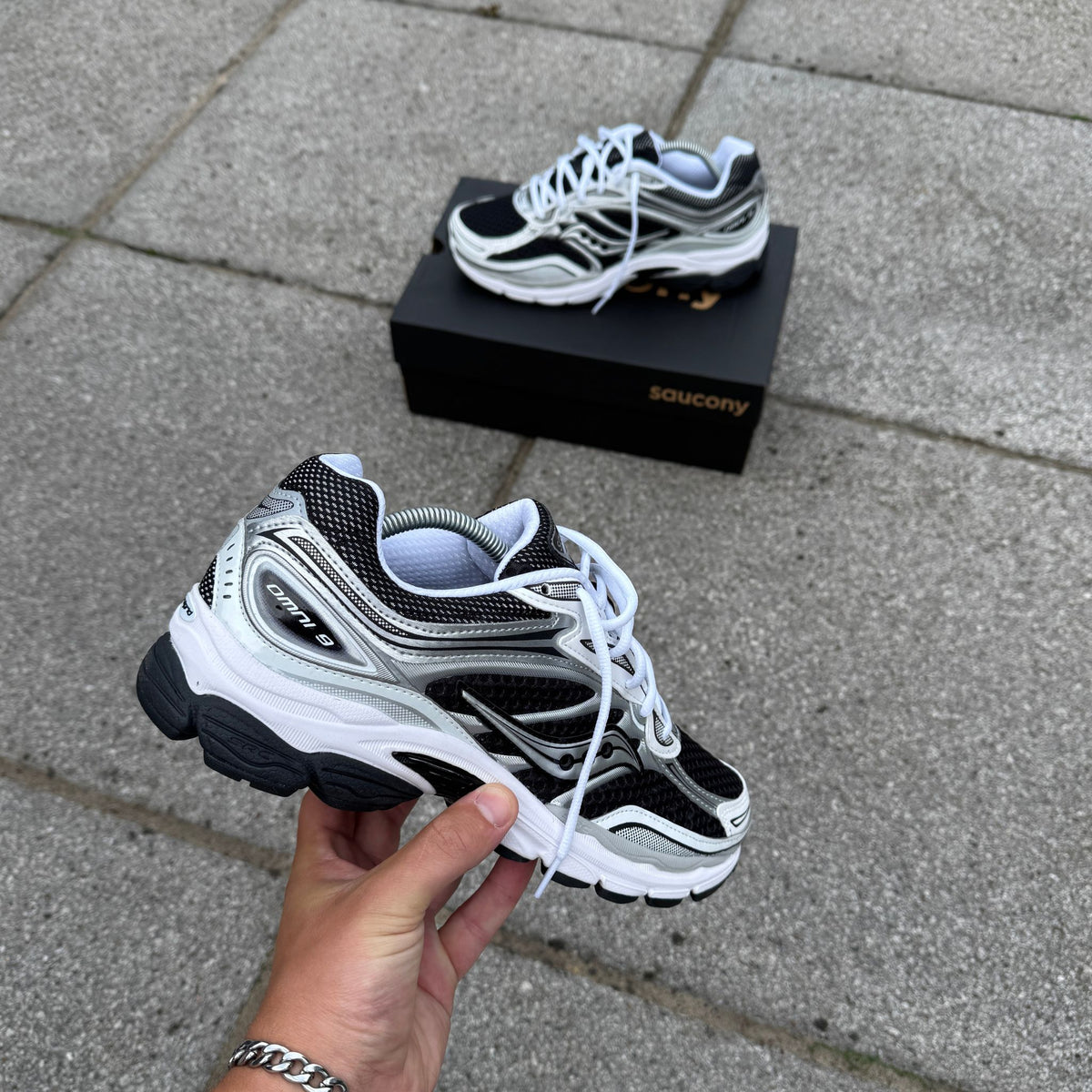 Saucony ProGrid Omni 9 Black White held from the rear showing the sculpted heel and side panelling