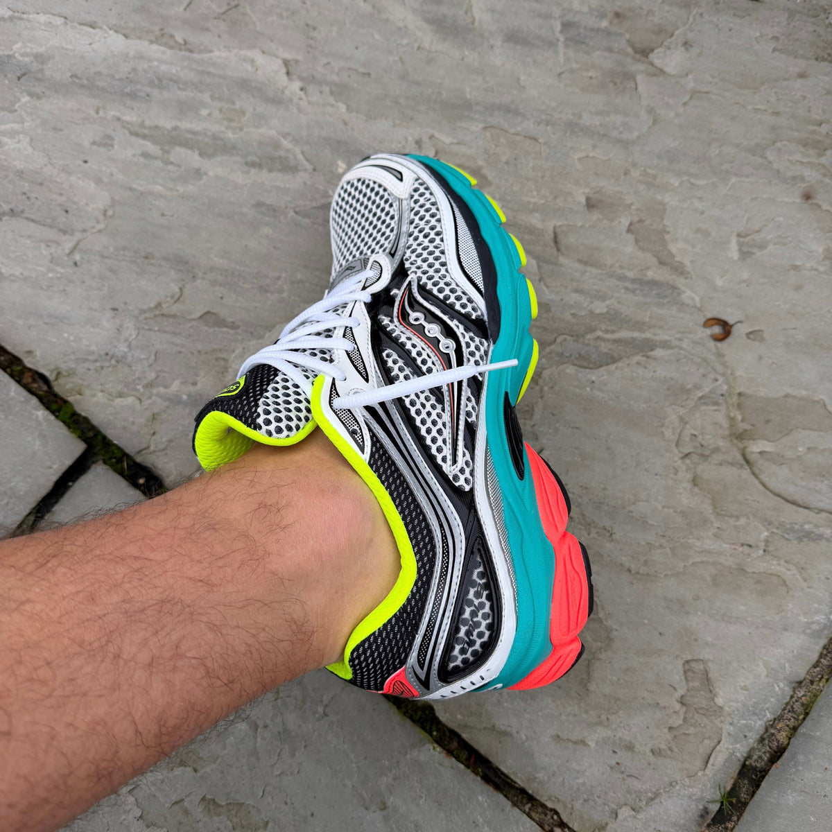 Close-up of Saucony ProGrid Omni 9 Silver Mutant showing the silver upper, turquoise accents and neon yellow laces