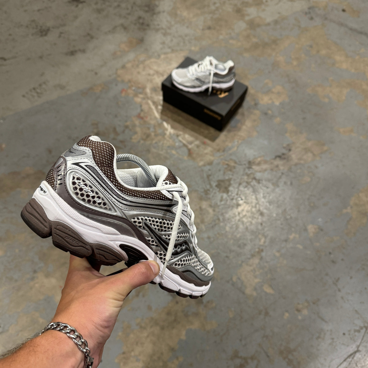 Saucony ProGrid Omni 9 White Brown trainer held in hand