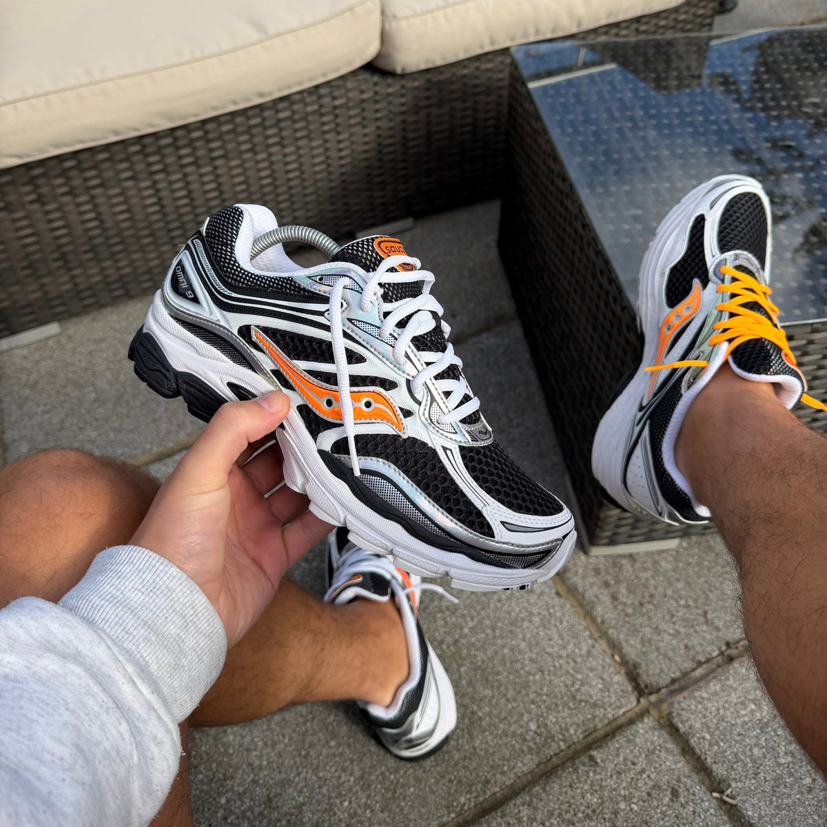 Saucony ProGrid Omni 9 White Orange trainer held in hand showing the side profile and orange detailing