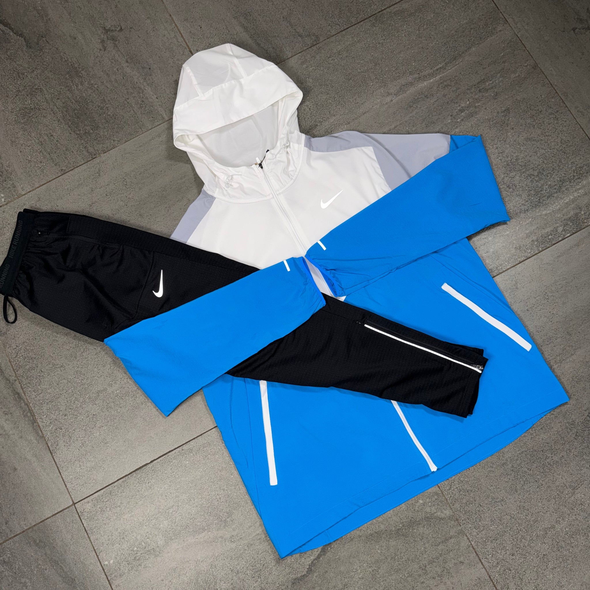 White Wolf Grey and blue Nike Windrunner laid alongside black Phenom running pants